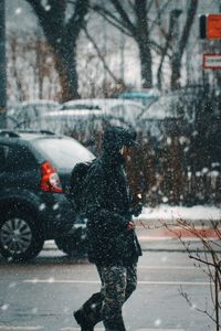 Man walking on city street in snow during winter