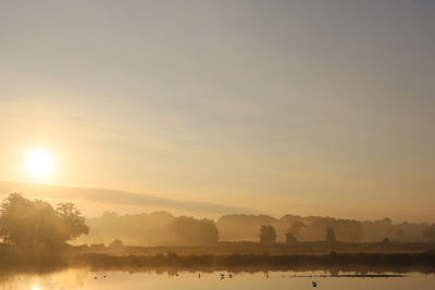 Scenic view of lake against sky during sunset