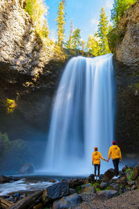 Rear view of man standing against waterfall