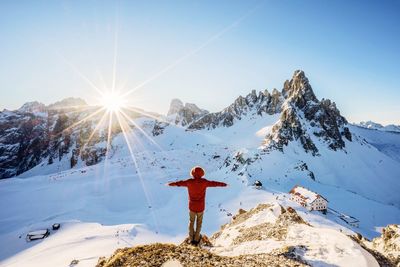 Woman standing on snow covered mountain against clear sky