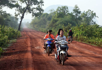 People riding motor scooters on road