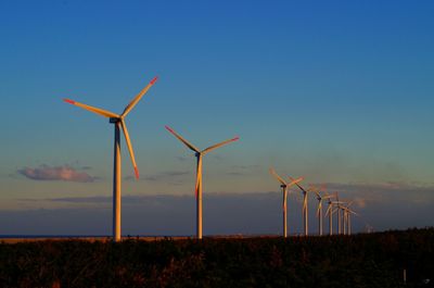 Windmills on field against sky during sunset