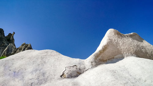 Low angle view of chalky mountains against clear blue sky