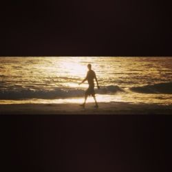 Silhouette people on beach at sunset