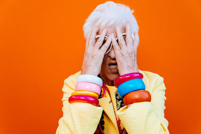 Portrait of tensed senior woman wearing eyeglasses against red background