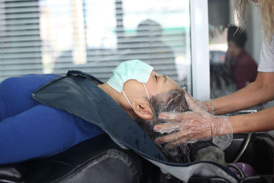 Midsection of hairdresser washing woman hair in salon