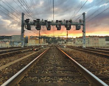 Railroad tracks against cloudy sky during sunset