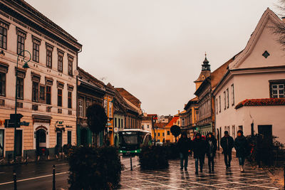 Group of people walking on street amidst buildings in city