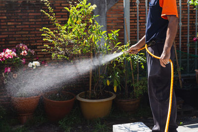 Termite controler spraying cemicals outside the house into the soil and wooden deck.