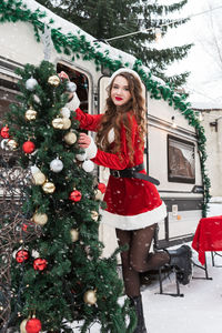 Full length of woman standing by christmas tree