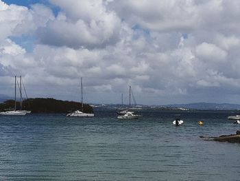 Sailboats moored on sea against sky