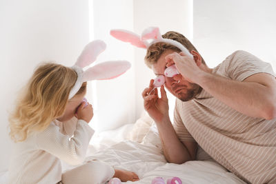 Man and two years old toddler girl, kid wearing bunny ears play with eggs.easter holiday with family 