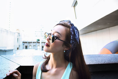 Close-up of beautiful woman wearing sunglasses looking away outside building