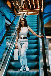 Young brunette latina attractive woman with shopping bags on escalator in the fashion store mall.