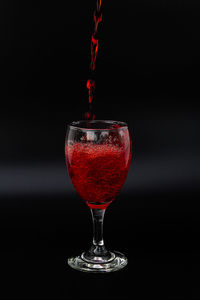 Close-up of red wineglass against black background