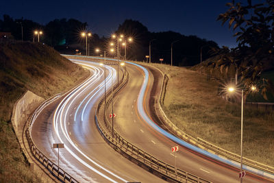 Highway at night lights. fast car light path, trails and streaks on interchange bridge road
