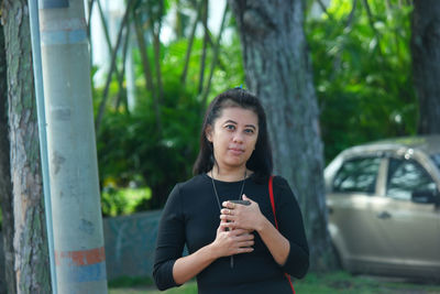 Portrait of woman standing against tree trunk