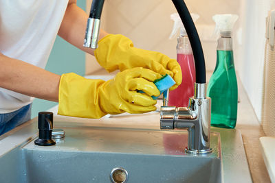 Woman cleaning kitchen sink with water tap