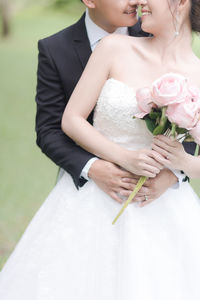 Midsection of bridal couple embracing outdoors