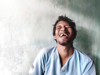 Portrait of smiling young man looking away against wall