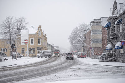 Snow covered road against clear sky in city