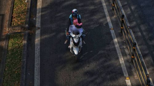 High angle view of people riding motorcycle on road