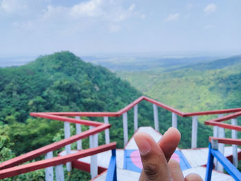 Cropped image of person on railing against sky