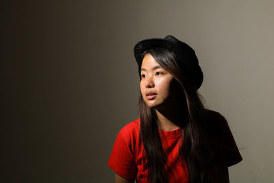 Portrait of beautiful young woman against black background
