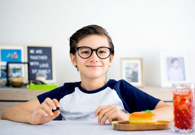 Portrait of smiling boy holding ice cream on table