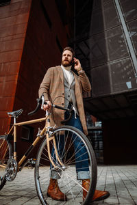 Low angle view of businessman with bicycle. walking