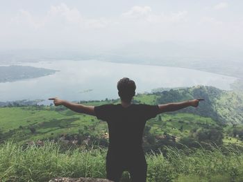 Rear view of man with arms outstretched standing on land