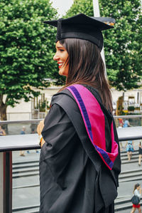 Portrait of beautiful young woman standing against trees