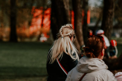 Rear view of woman standing against trees