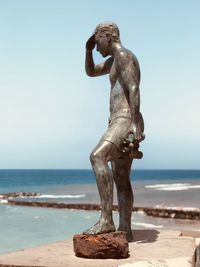 Statue on beach against sky