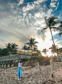 Rear view of woman walking on beach against sky