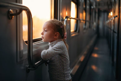 Rear view of boy looking through window