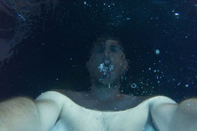 Shirtless man swimming in sea