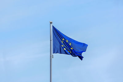 Low angle view of flag against blue sky