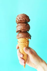 Close-up of hand holding ice cream against blue sky