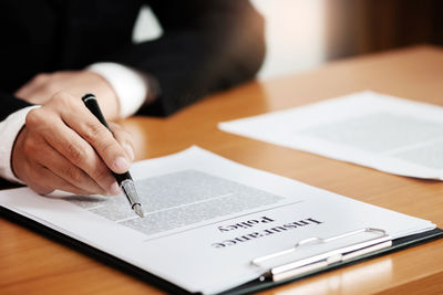 Midsection of man reading book on table