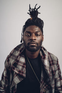 Young man with locs hairstyle standing in front of white background