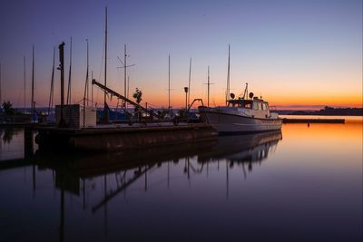 Boats moored in harbor at sunset