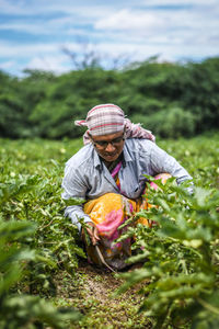 Farmer working in farm against cloudy sky