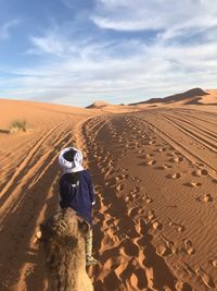 Man standing on sand dune in desert against sky