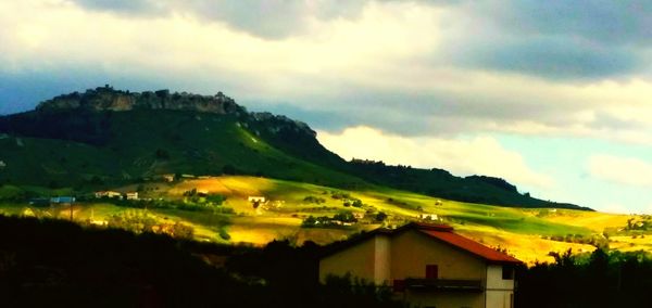 Houses on landscape against cloudy sky