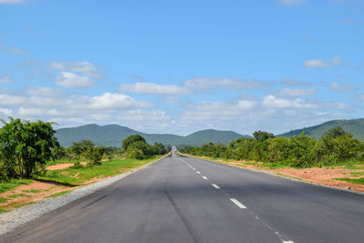 Empty road along trees and plants against sky, the great east road, zambia 