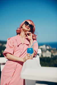 Young woman wearing sunglasses while standing against sky