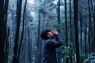 Side view of young man in forest