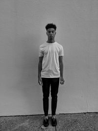 Full length portrait of young man standing against wall