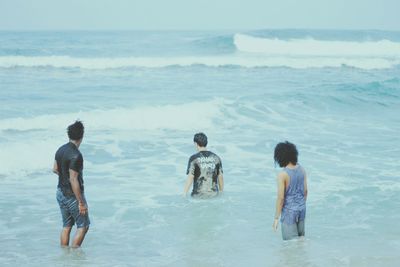 Boys standing on beach against sky